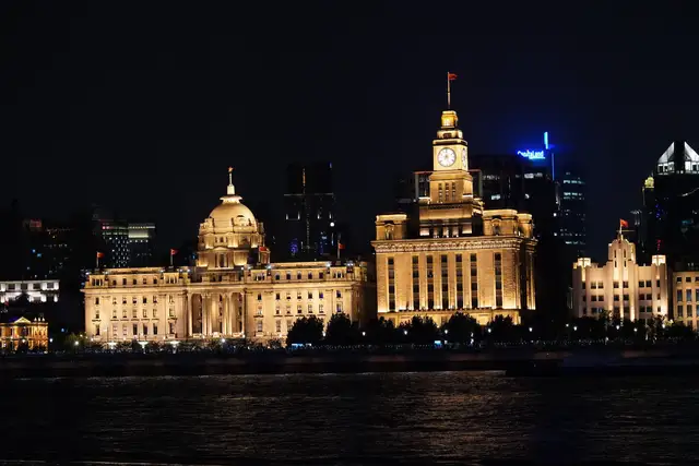 The floodlit Customs House clock tower and the domed former HSBC Building on the Bund in Shanghai, seen across the Huangpu River at night.
