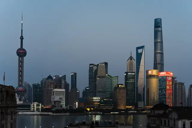 The Lujiazui skyline in Shanghai at blue hour, with the Oriental Pearl Tower on the left and Shanghai Tower on the right above the Huangpu River.